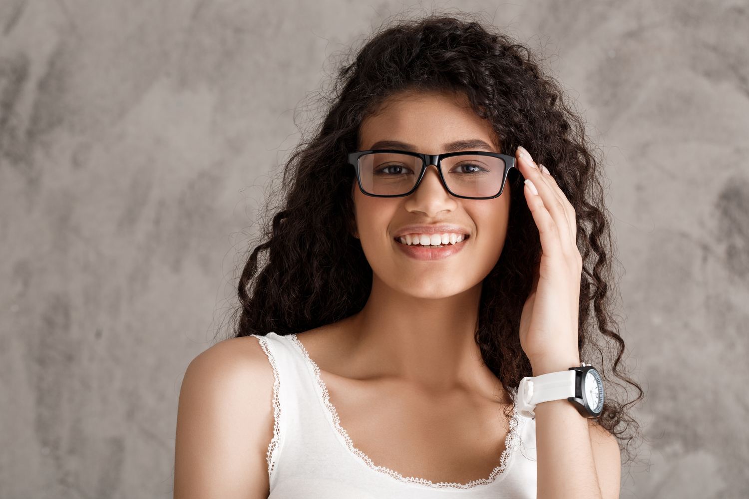 Mulher de cabelo cacheado sorrindo com óculos de grau