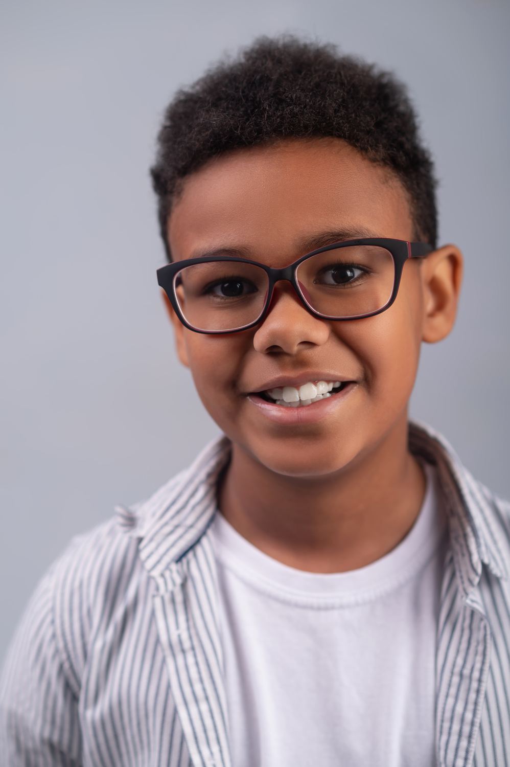 Menino sorrindo com óculos de grau